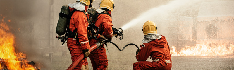 Firefighters using fire hose extinguishing burning fire